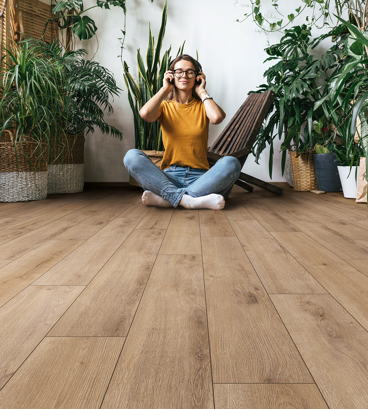 Serene space with K502 Flax River Oak laminate flooring, surrounded by plants and natural light and a woman enjoying music