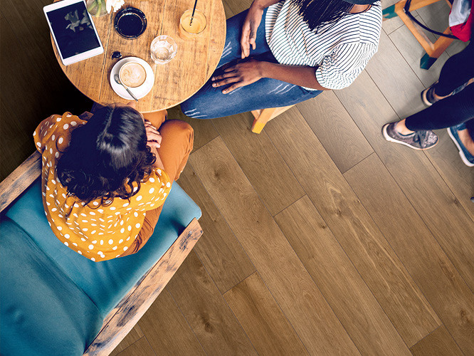 A group of people sitting in a café with beautiful SPC flooring Humidor 5+1 underneath.