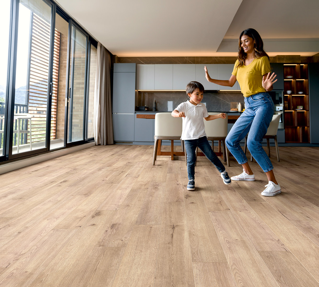 K501 Sand River Oak laminate flooring in a cozy living room with mother and child dancing