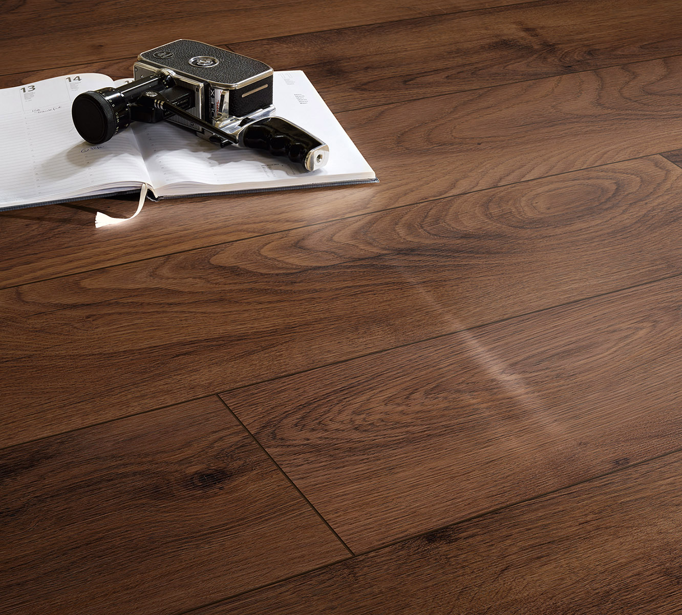 Natural oak texture of K505 Tobacco Manor Oak laminate flooring with rich knots and V-groove, styled with magazine and camera
