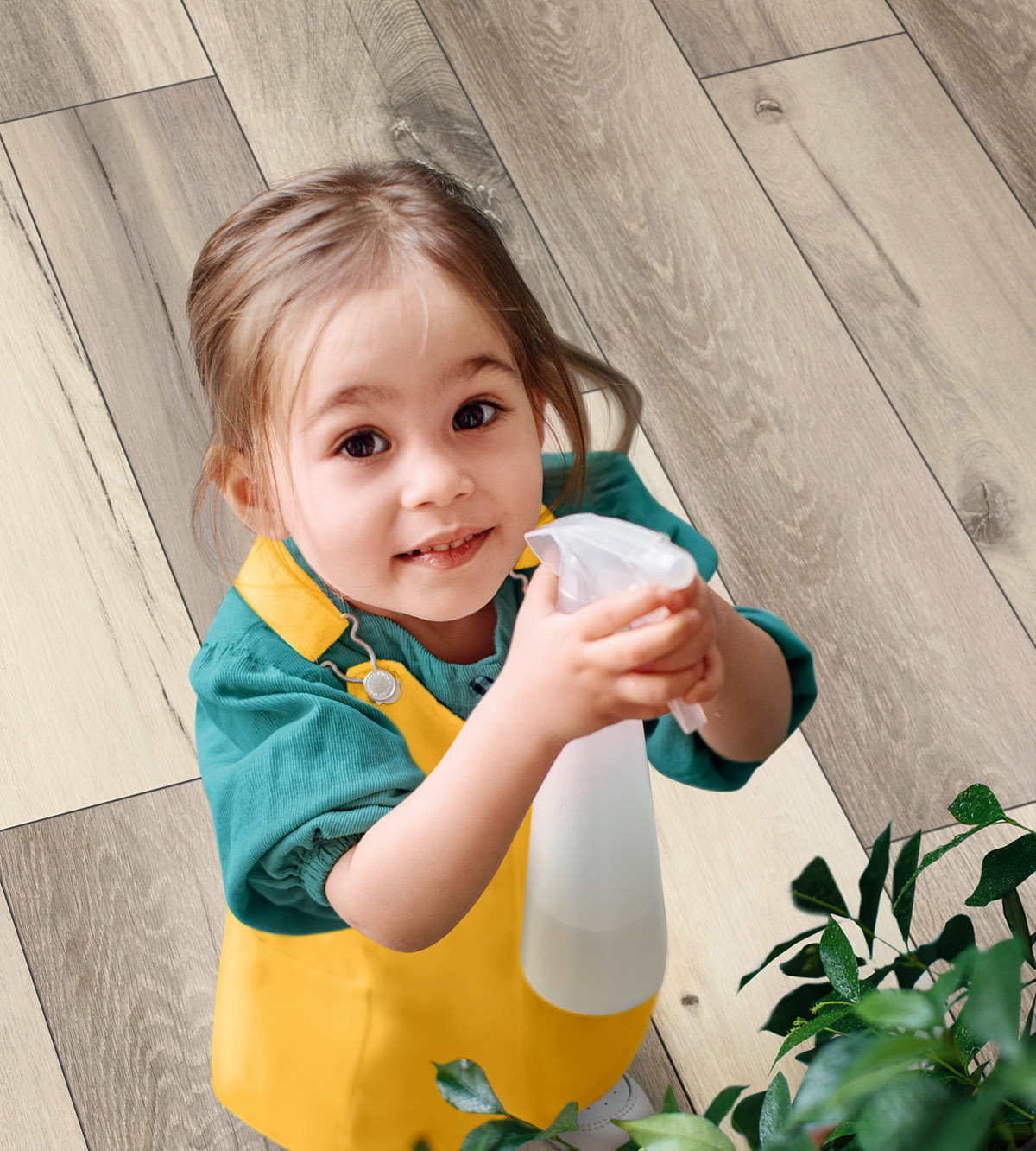 K506 Lunar Range Oak laminate flooring with moisture-resistant technology – child playfully spraying water on a flower